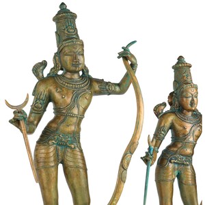 Puede incluir: Dos estatuas deidades de color bronce. Las estatuas tienen rasgos faciales detallados, tocados ornamentados y est&aacute;n adornadas con joyas. Una estatua sostiene un b&aacute;culo curvo y un arco, mientras que la otra sostiene una espada. Las estatuas tienen una apariencia envejecida y antigua.