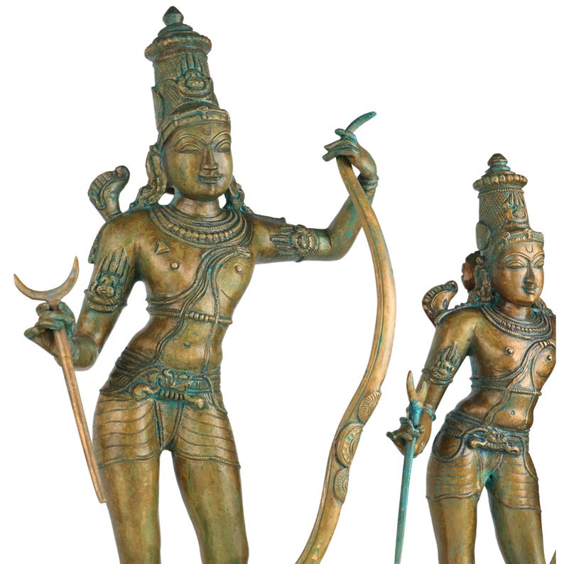 Puede incluir: Dos estatuas deidades de color bronce. Las estatuas tienen rasgos faciales detallados, tocados ornamentados y est&aacute;n adornadas con joyas. Una estatua sostiene un b&aacute;culo curvo y un arco, mientras que la otra sostiene una espada. Las estatuas tienen una apariencia envejecida y antigua.