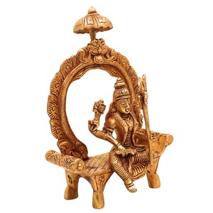 Puede incluir: Estatua dorada de una figura sentada, posiblemente una deidad, con detalles intrincados. La figura est&aacute; sentada en una estructura similar a un banco dentro de un marco circular ornamentado. Un elemento en forma de paraguas corona el marco. La estatua tiene una corona detallada y sostiene objetos.