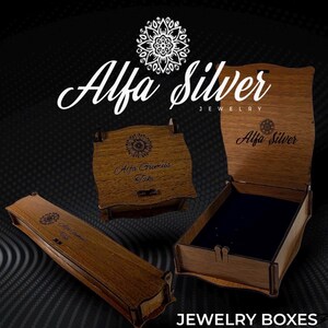 May include: Three wooden jewelry boxes with a dark brown finish. One box is long and rectangular, one is square and closed, and one is square and open with a black interior. Each box features the Alfa Silver logo and text engraved on the surface.