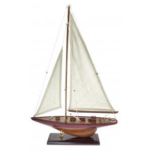 Könnte beinhalten: Ein Modellsegelschiff mit einem burgunderfarbenen Rumpf und cremefarbenen Segeln. Das Holzboot hat ein detailliertes Deck und ist auf einem dunklen rechteckigen Sockel montiert. Der Mast und die Spieren sind dunkelbraun.