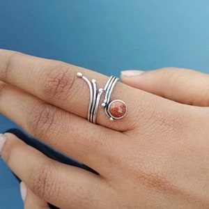Puede incluir: Un anillo de plata con una piedra de sol marrón engastada en una banda retorcida.