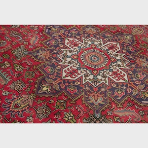 May include: A red area rug with an intricate central starburst design. The rug features a deep red field with a large, multi-pointed star in the center, bordered by a dark blue and white pattern. Floral and geometric motifs are incorporated throughout.