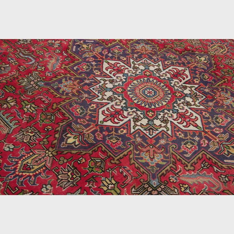 May include: A red area rug with an intricate central starburst design. The rug features a deep red field with a large, multi-pointed star in the center, bordered by a dark blue and white pattern. Floral and geometric motifs are incorporated throughout.