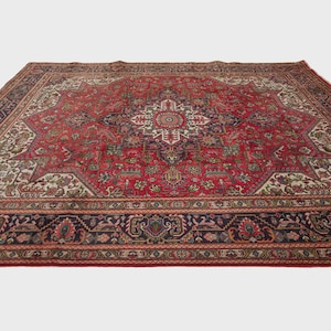 May include: A large rectangular area rug featuring a deep red field with a central cream and navy blue star-shaped medallion. The rug is decorated with intricate floral and geometric patterns throughout, finished with a wide dark navy border.