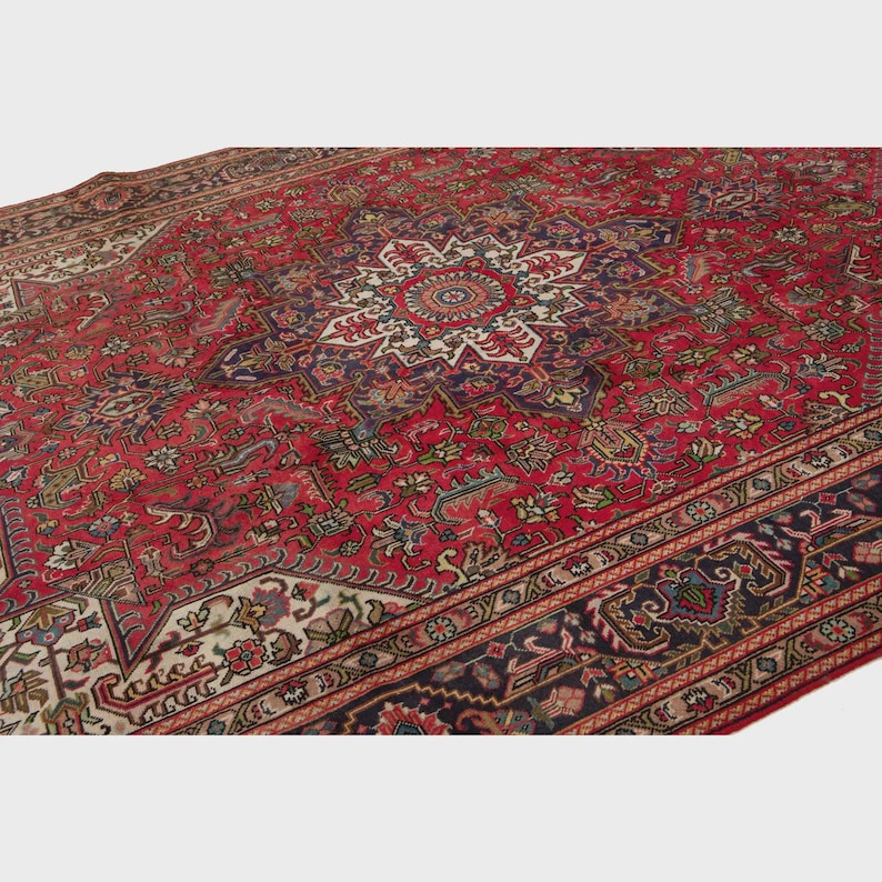 May include: A large, ornate red rug with a central medallion design and intricate floral patterns. The rug features a border with dark blue and cream accents, showcasing a traditional Persian style. The rug's detailed design and rich colors create a luxurious feel.