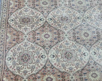 May include: A vintage rug with a repeating pattern of floral motifs in shades of beige, brown, and pink. The rug has a distressed look and a worn texture.