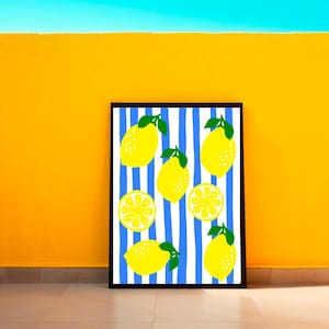 Puede incluir: Una impresi&oacute;n art&iacute;stica enmarcada con un dise&ntilde;o de lim&oacute;n. La obra presenta limones amarillos con hojas verdes sobre un fondo de rayas verticales azules y blancas. El marco es negro y el fondo es una pared amarilla vibrante.