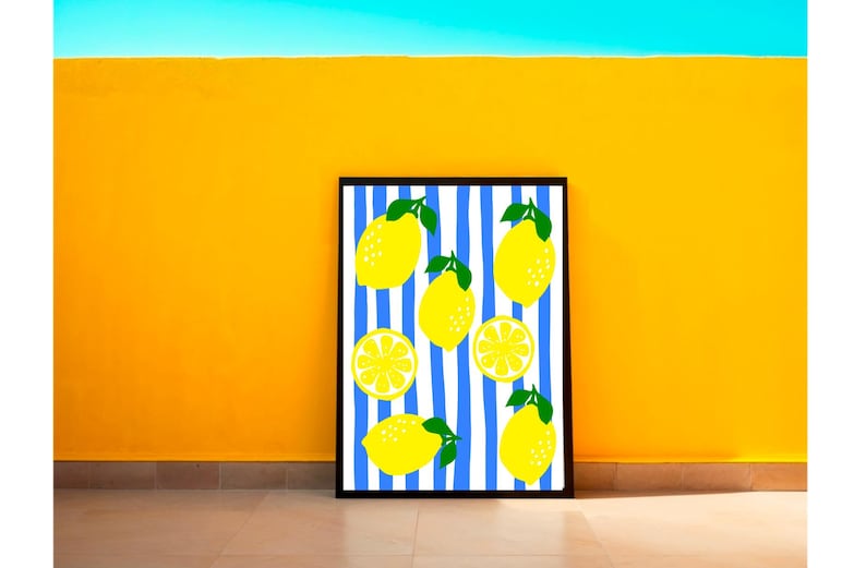Puede incluir: Una impresi&oacute;n art&iacute;stica enmarcada con un dise&ntilde;o de lim&oacute;n. La obra presenta limones amarillos con hojas verdes sobre un fondo de rayas verticales azules y blancas. El marco es negro y el fondo es una pared amarilla vibrante.