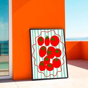 Puede incluir: Una impresi&oacute;n art&iacute;stica enmarcada con una vibrante ilustraci&oacute;n de tomates rojos con tallos verdes. Los tomates est&aacute;n dispuestos sobre un fondo a rayas con un borde ondulado rojo. La obra de arte est&aacute; colocada contra una pared naranja.