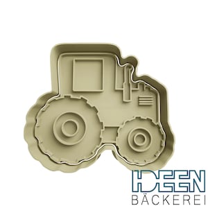 May include: A beige plastic cookie cutter shaped like a tractor with two large wheels and a smaller wheel at the back. The tractor has a rectangular window and a small exhaust pipe.