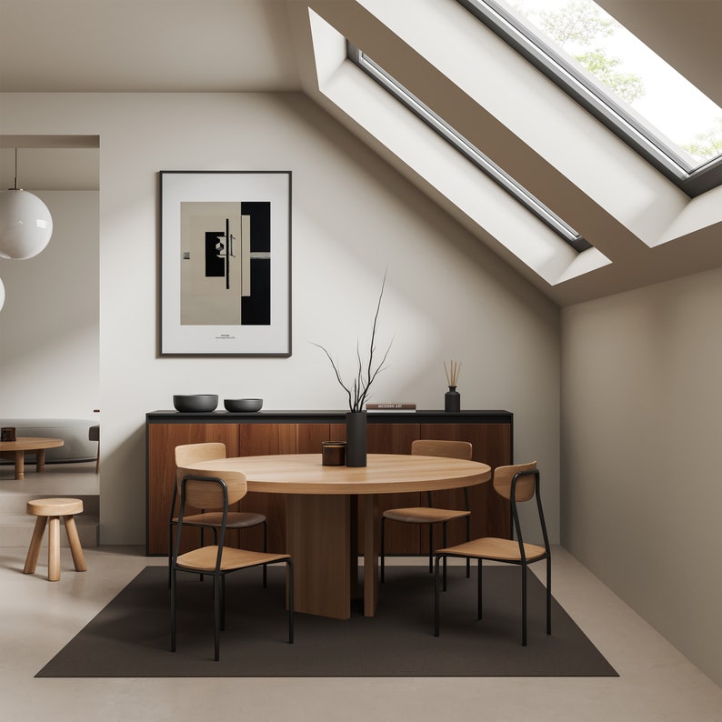 May include: A round wooden dining table with four black metal chairs. The table is set with a vase of branches and a bowl of fruit. The room has a modern design with white walls and a large window.