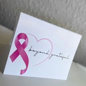 May include: A white card with a pink ribbon and a pink heart. The text "beyond grateful" is written in black cursive.