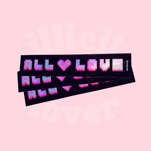 May include: Three holographic stickers with the text "ALL LOVE" in pixelated pink letters with a pink pixelated heart in between the words. The stickers are on a black background and have a holographic finish.