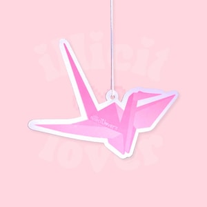 May include: Pink origami crane paper car air freshener with the text "#lilctloverz" hanging from a string.