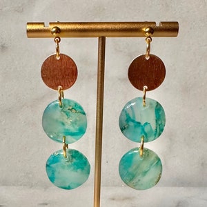 May include: Gold tone dangle earrings with three round turquoise and gold agate stones and a gold tone disc at the top.