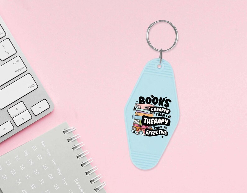 May include: A light blue motel key chain with the text "BOOKS ARE CHEAPER THAN THERAPY TWICE AS EFFECTIVE" and a stack of colorful books with a rainbow and clouds.