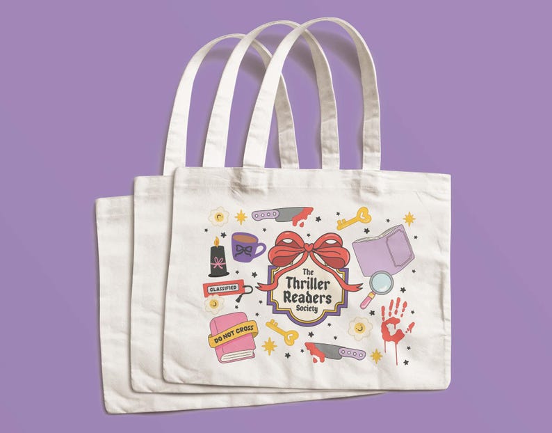 May include: Three white tote bags with cream-colored handles. Each bag features a colorful design with a bow, knives, keys, a magnifying glass, a handprint, and the text "The Thriller Readers Society."