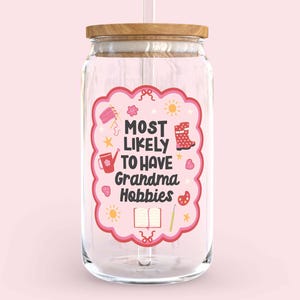Może przedstawiać: Przezroczysty szklany słoik z drewnianą pokrywką i słomką. Słoik ma r&oacute;żową etykietę z napisem "MOST LIKELY TO HAVE Grandma Hobbies" i ilustracjami rzemiosła. Tło jest w kolorze miękkiego r&oacute;żu.