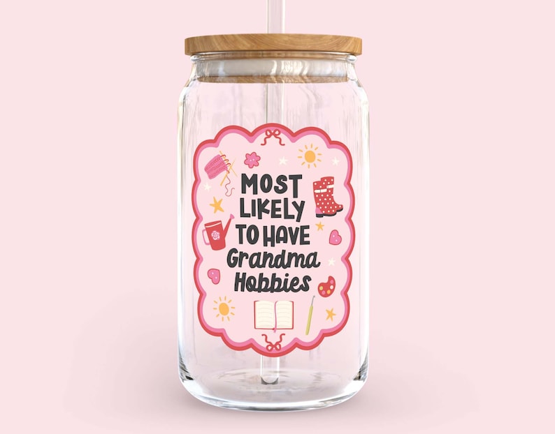 Może przedstawiać: Przezroczysty szklany słoik z drewnianą pokrywką i słomką. Słoik ma r&oacute;żową etykietę z napisem "MOST LIKELY TO HAVE Grandma Hobbies" i ilustracjami rzemiosła. Tło jest w kolorze miękkiego r&oacute;żu.