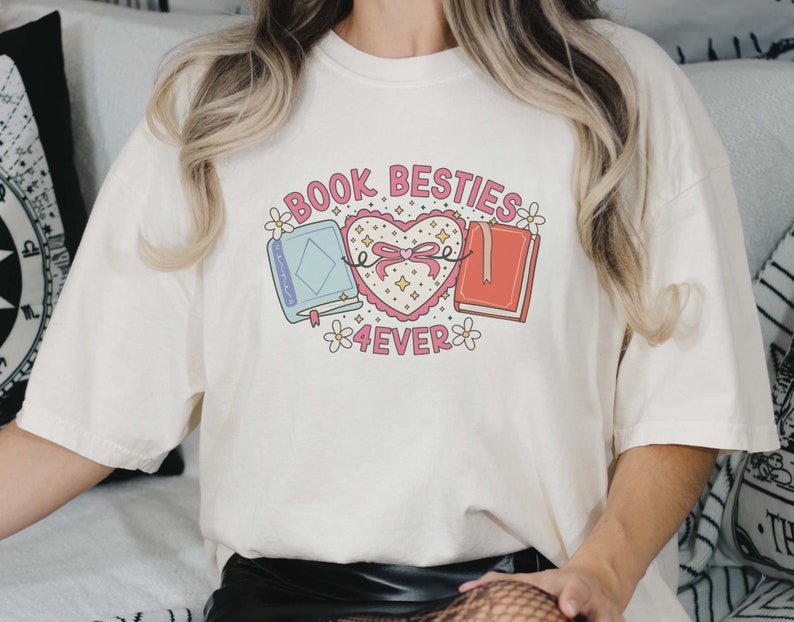 May include: White t-shirt with a graphic of two books tied together with a pink ribbon and a heart that says "Book Besties 4ever".