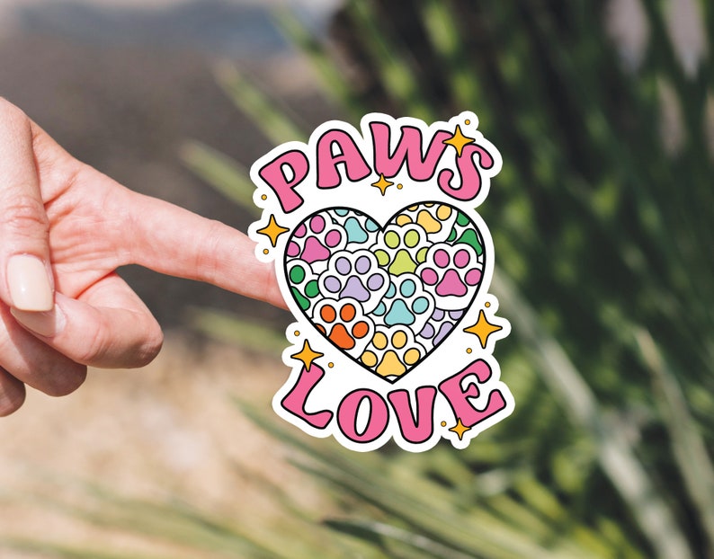 May include: A pink and white sticker with the words "PAWS LOVE" and a heart made of paw prints in rainbow colors.