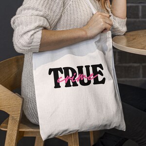 May include: White tote bag with black text that says "TRUE crime" in a bold font. The word "crime" is in pink.