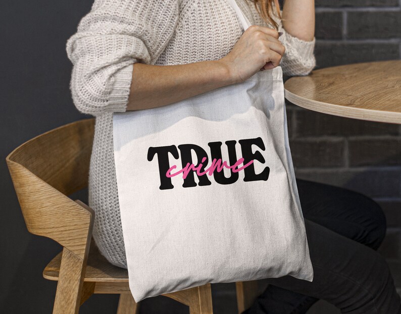 May include: White tote bag with black text that says "TRUE crime" in a bold font. The word "crime" is in pink.