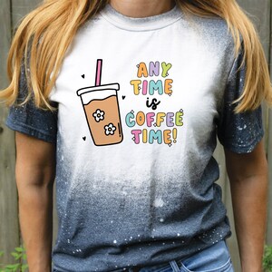 May include: A white t-shirt with a blue ombre effect on the bottom half. The shirt features a graphic of a coffee cup with a straw and the text "ANY TIME is COFFEE TIME!"