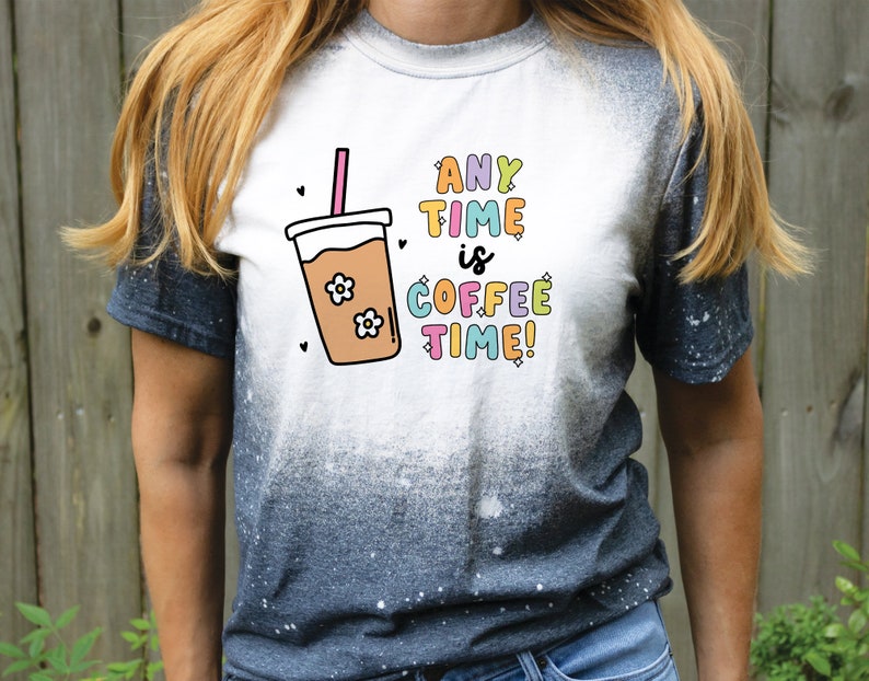 May include: A white t-shirt with a blue ombre effect on the bottom half. The shirt features a graphic of a coffee cup with a straw and the text "ANY TIME is COFFEE TIME!"