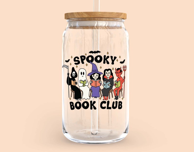 Puede incluir: Un tarro de vidrio transparente con tapa de madera y pajita. El tarro presenta un gr&aacute;fico colorido de personajes de Halloween de dibujos animados leyendo libros, con las palabras "Spooky Book Club" arriba y abajo de los personajes. El dise&ntilde;o incluye una parca, un fantasma, una bruja, un vampiro y un diablo.