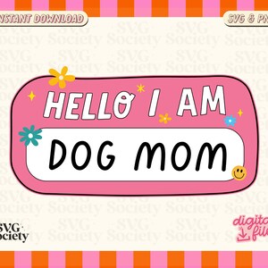 Peut inclure: &Eacute;tiquette de nom rose et blanche avec le texte "Hello I am Dog Mom" en lettres noires. L'&eacute;tiquette de nom a une bordure blanche et est d&eacute;cor&eacute;e de petites fleurs et d'un visage souriant.