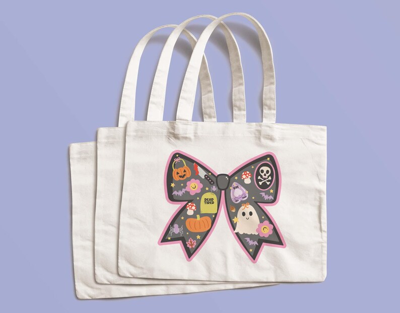 May include: Three white canvas tote bags with a Halloween design. The design features a black bow shape with a pink outline, and is filled with Halloween icons such as a pumpkin, ghost, and skull and crossbones.