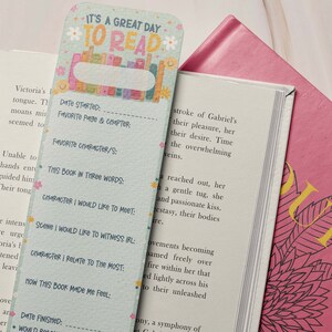 May include: A green and blue bookmark with a floral design and the text "It's a great day to read". The bookmark has sections for recording information about a book, such as the date started, favorite page and chapter, favorite character, and how the book made the reader feel.