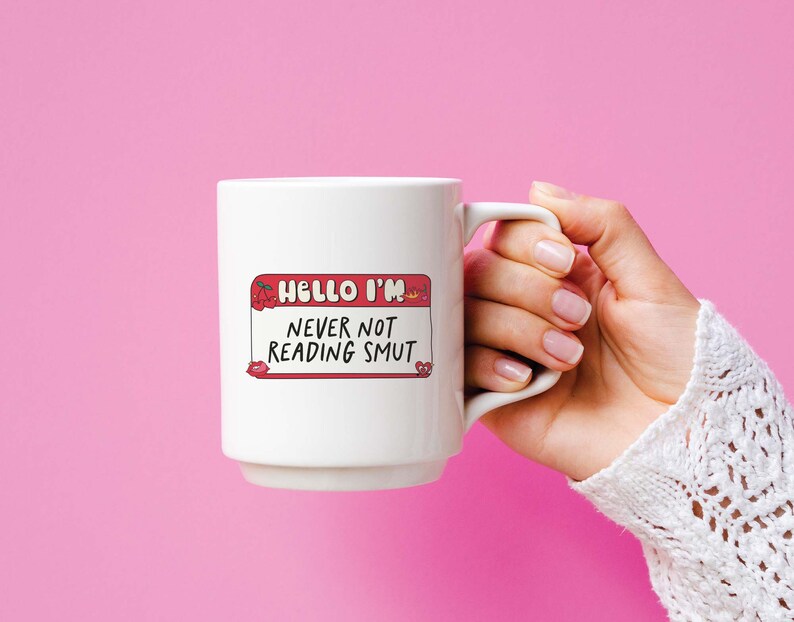 May include: White ceramic mug with a red and white name tag that says "Hello I'm Never Not Reading Smut".