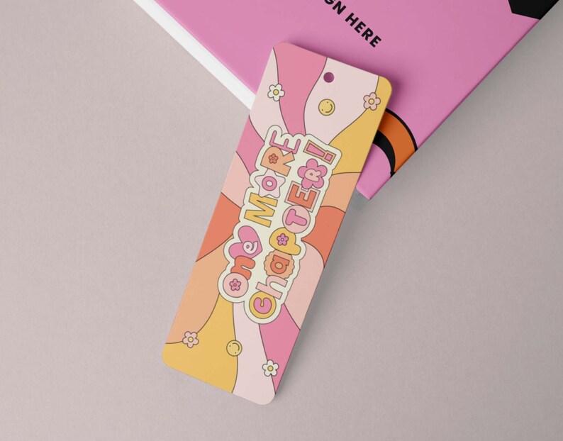K&ouml;nnte beinhalten: Ein rosa und gelbes Lesezeichen mit Retro-Design. Das Lesezeichen hat ein wellenf&ouml;rmiges Muster und den Text "one more chapter!" in einem rosa Herz.