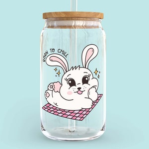 May include: A clear glass water bottle with a wooden lid and a straw. The bottle has a cartoon image of a white bunny with pink ears and the text "Born to Chill".