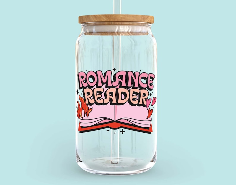 May include: A clear glass jar with a wooden lid and a straw. The jar has a pink and red graphic of a book with flames and hearts and the text "Romance Reader".