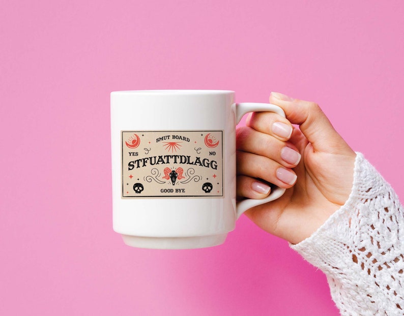 Puede incluir: Taza de cer&aacute;mica blanca con un gr&aacute;fico negro y rojo de una tabla Ouija con el texto "SMUT BOARD" y "STFUATTDLAGG".