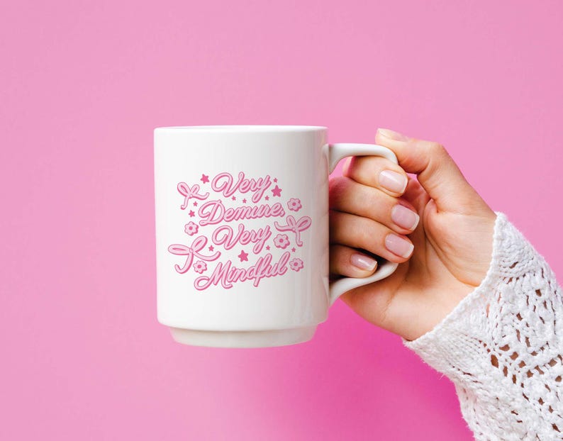 May include: White ceramic mug with a pink design that says "Very Demure, Very Mindful".