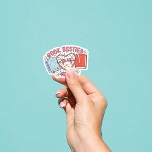 May include: A sticker with a pink heart and two books, one blue and one red, with the text "Book Besties" above the heart.