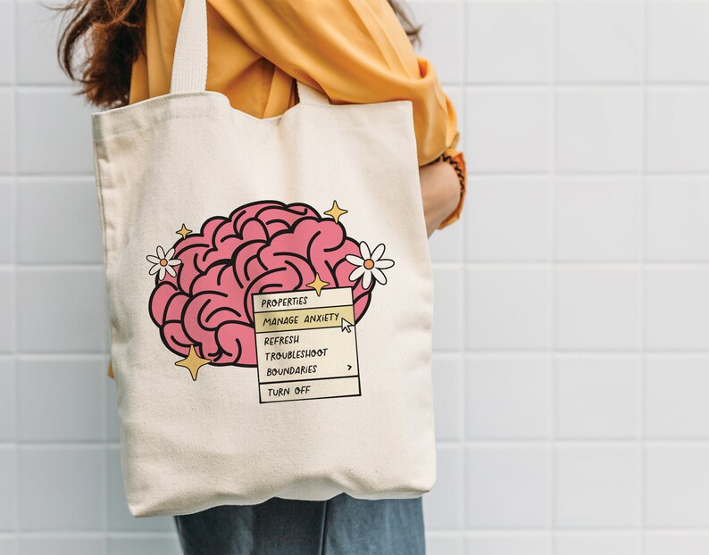May include: A white canvas tote bag featuring a pink brain illustration and a yellow menu bar with the text "PROPERTIES", "MANAGE ANXIETY", "REFRESH", "TROUBLESHOOT BOUNDARIES", and "TURN OFF".