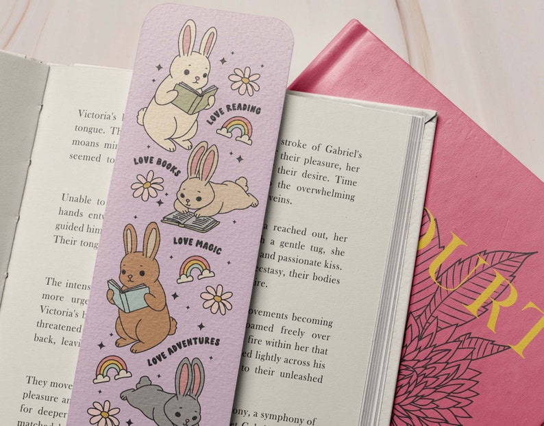 May include: A purple bookmark with illustrations of bunnies reading books. The bookmark has the text "Love Reading", "Love Books", "Love Magic", and "Love Adventures".