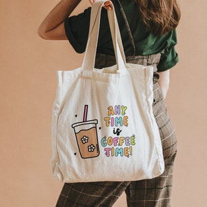 May include: A white canvas tote bag with a colorful graphic of a coffee cup and the text "Any Time is Coffee Time!" printed on it.