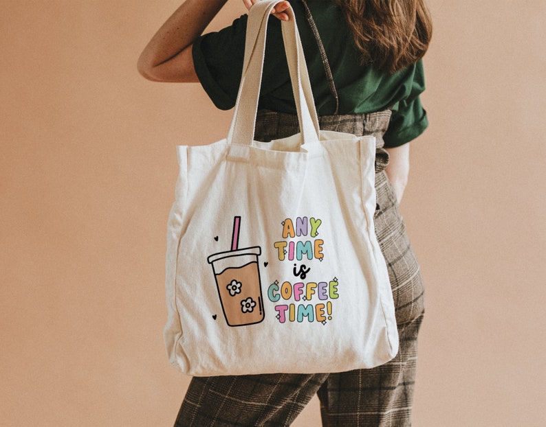 May include: A white canvas tote bag with a colorful graphic of a coffee cup and the text "Any Time is Coffee Time!" printed on it.