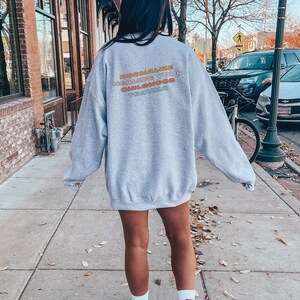 May include: Gray sweatshirt with the text "NORMALIZE HEALING YOUR CHILDHOOD TRAUMA" printed on the back in rainbow colors.