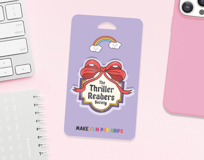 May include: A purple pop grip featuring a red bow and the words "The Thriller Readers Society." A rainbow and clouds graphic is above the bow. The text "MAKE FUN POP GRIPS" is at the bottom.