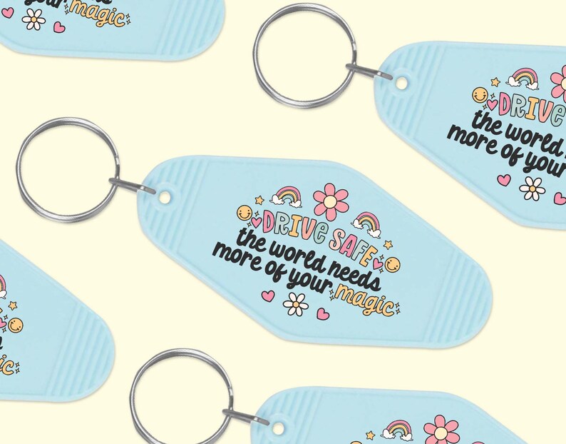 May include: Blue motel key chain with a white and pink design. The keychain features a rainbow, flowers, and the text "DRIVE SAFE the world needs more of your magic".