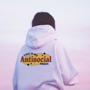 May include: White hoodie with the text "This is my Antisocial Hoodie" in a yellow oval with red text and black outlines. There are small stars around the oval.