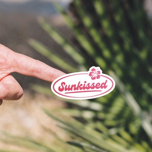 May include: White oval sticker with a pink hibiscus flower and the text "Sunkissed" in a pink cursive font.